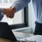 A woman and a man shaking hands over a legal document translation.